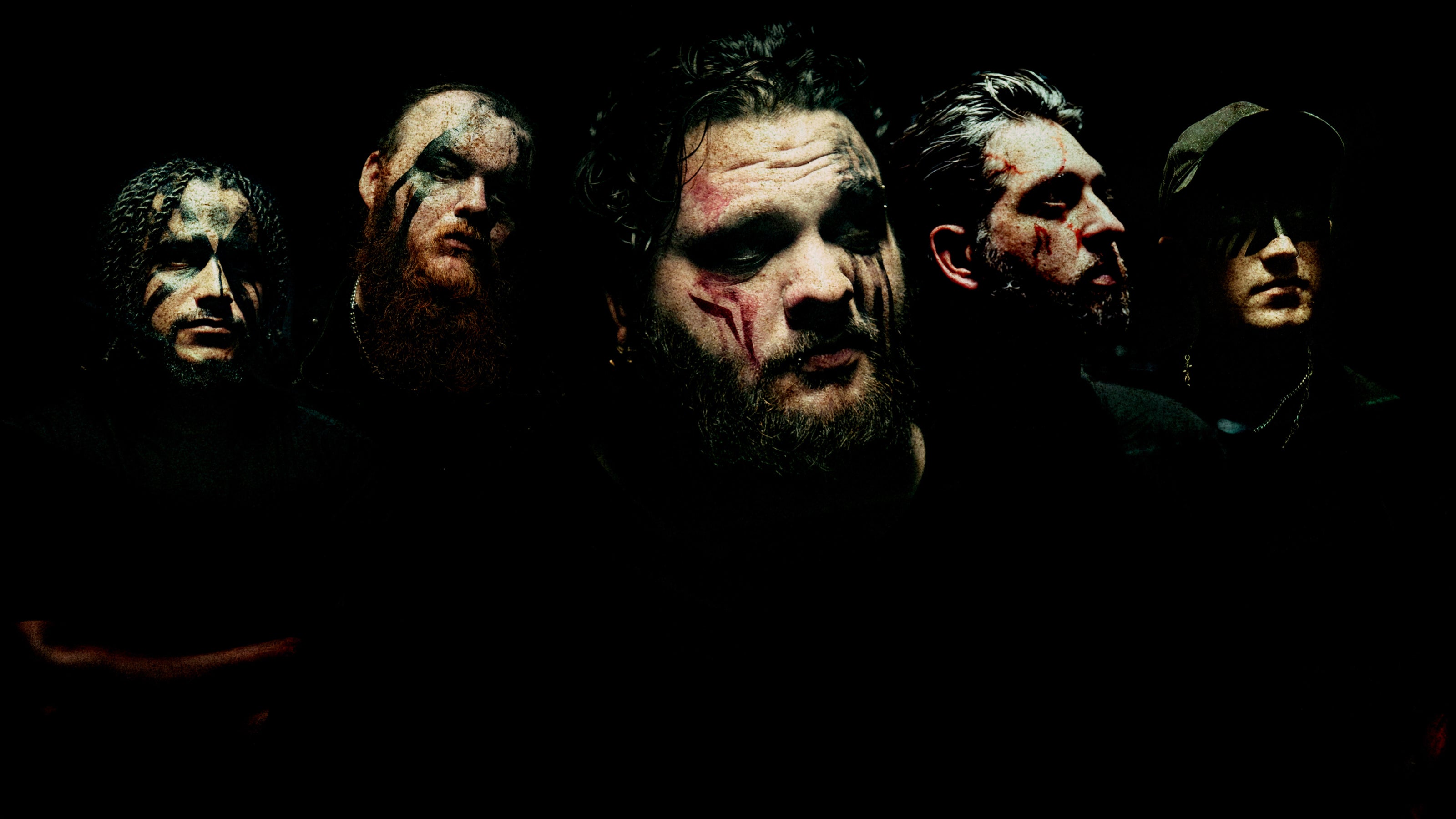 Five men with face paint posing against a dark background