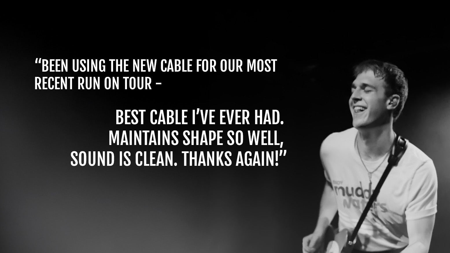 Person playing guitar on stage with text about a cable, against a dark background.