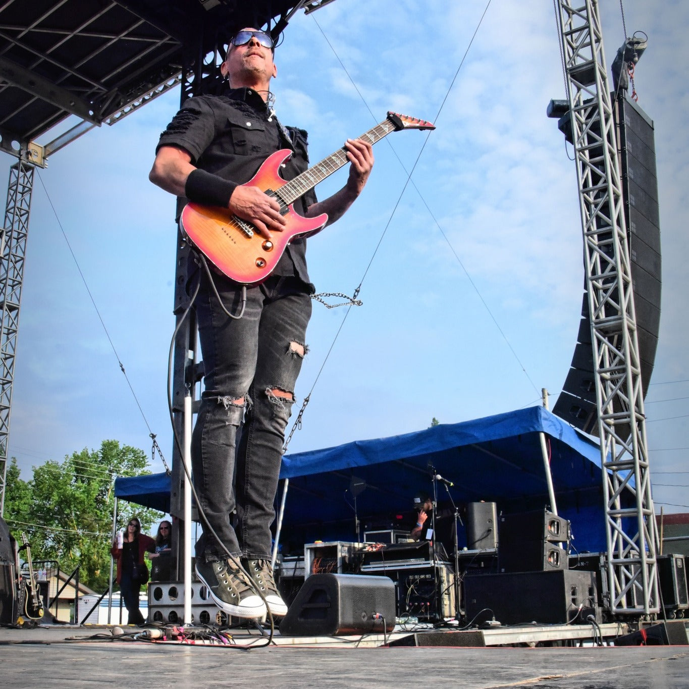 Guitarist jumping on stage while playing a red and yellow electric guitar