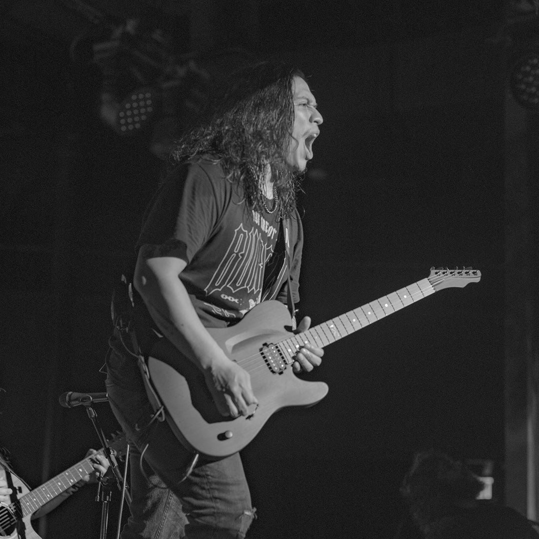 Long haired guitarist singing while playing an electric guitar on stage