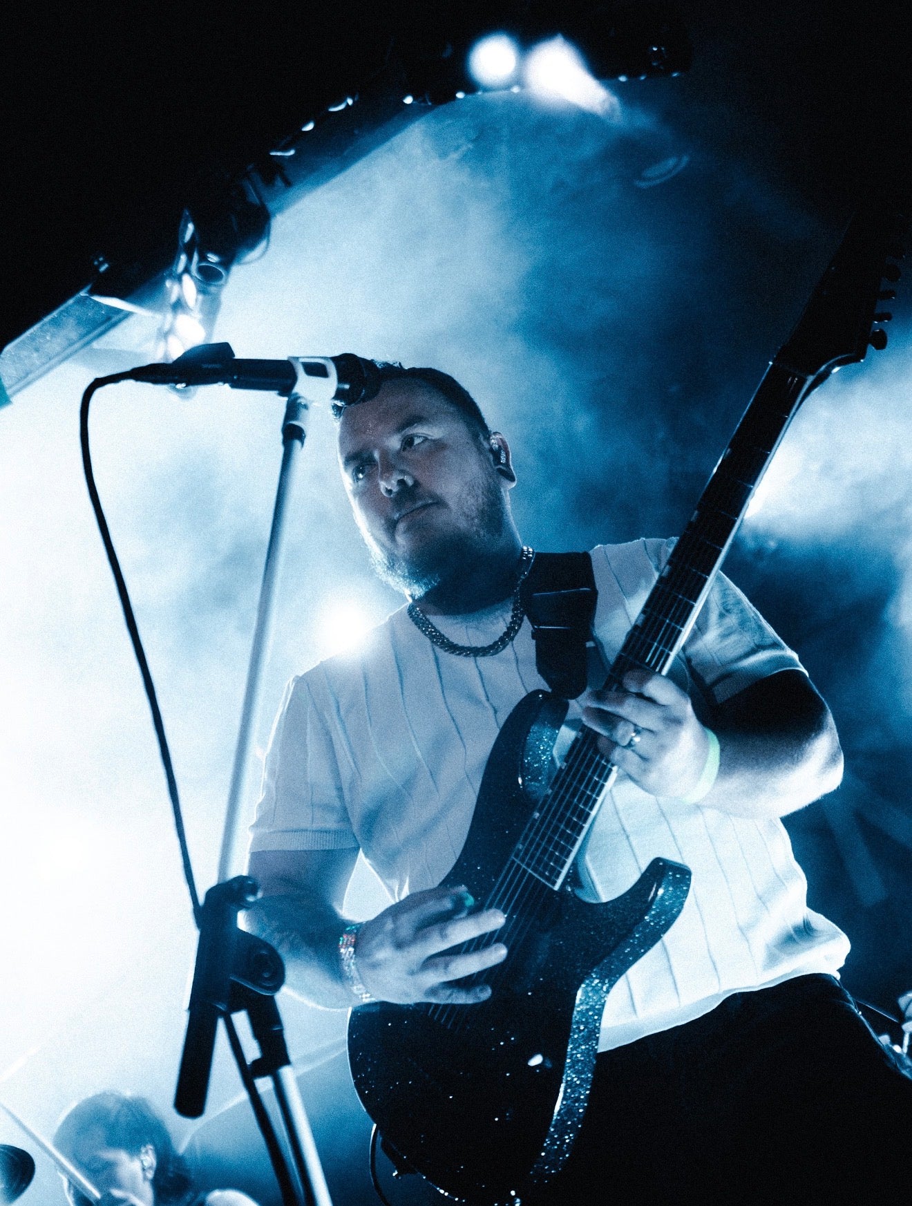 Musician playing electric guitar on stage under blue spotlight